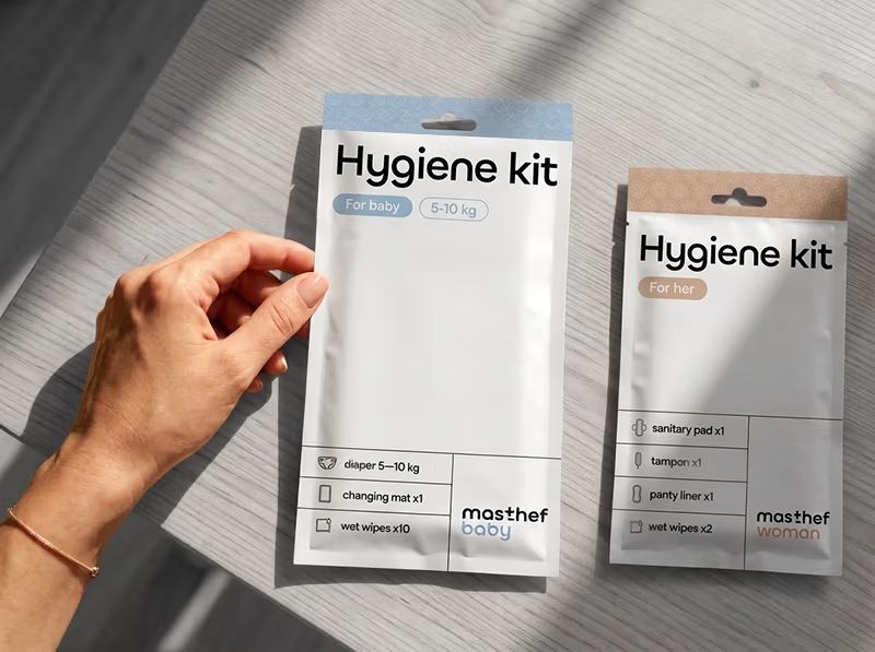A hand holding two masthef hygiene packs – the baby variant and the woman variant